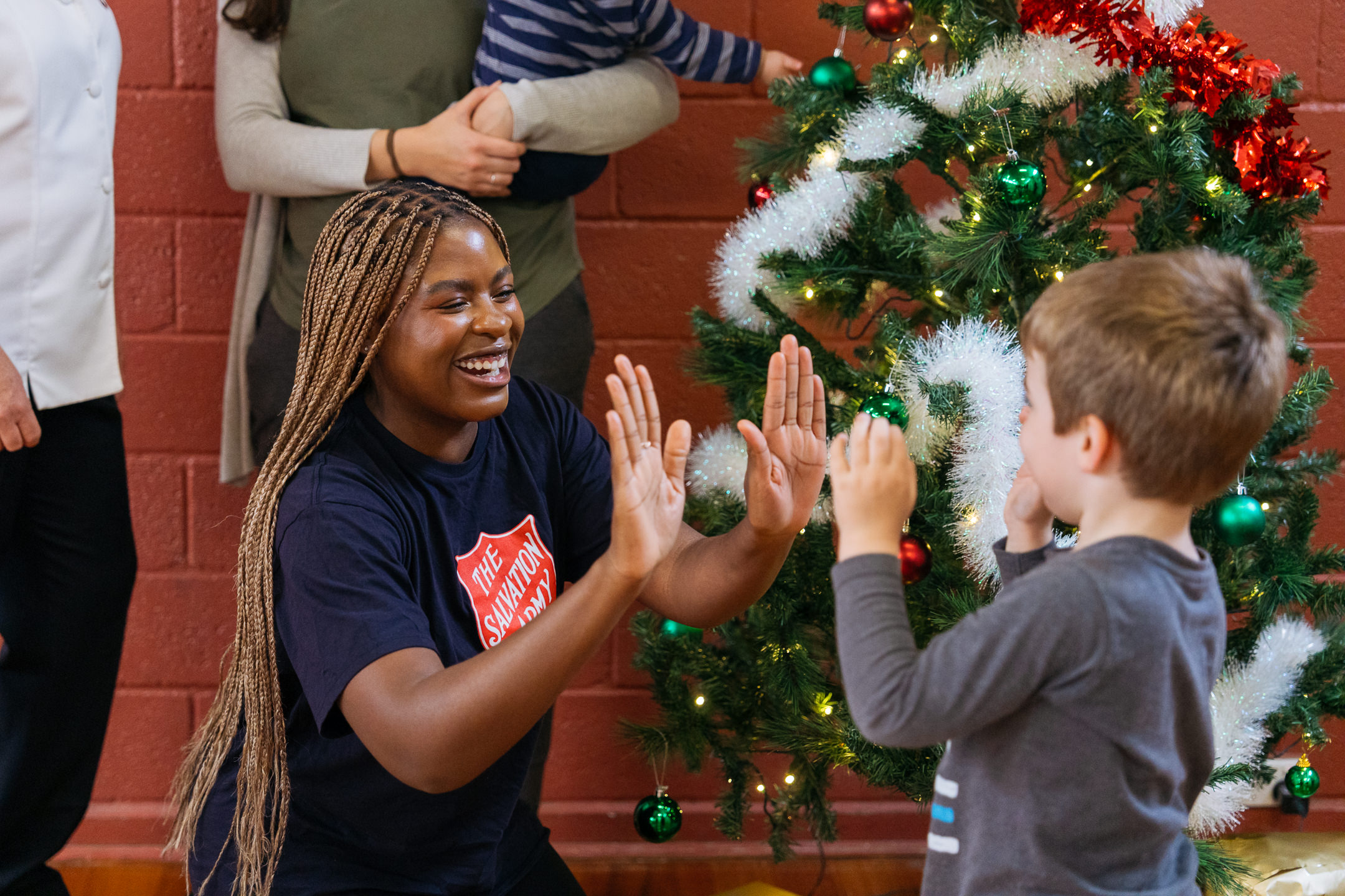 A Salvos woman hi-fiving a little boy