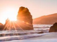 Sunrise appears through rock in the ocean