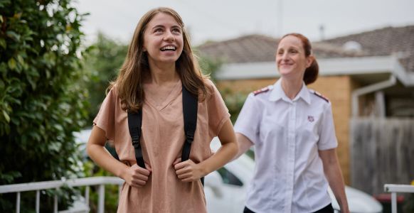 Naomi walking with her two school children, smiling.