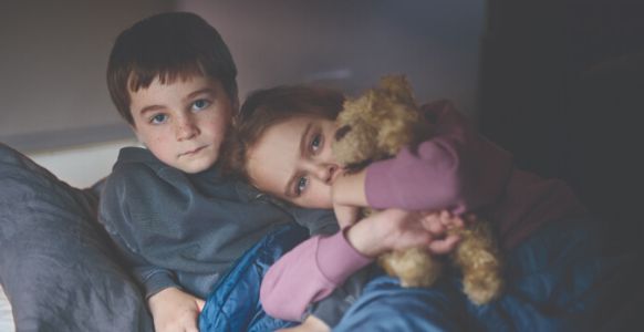 Suzi's son and daughter, who is hugging a teddy bear, looking for support.