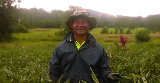 Manrhing as a refugee in India, standing in a grassy field. 