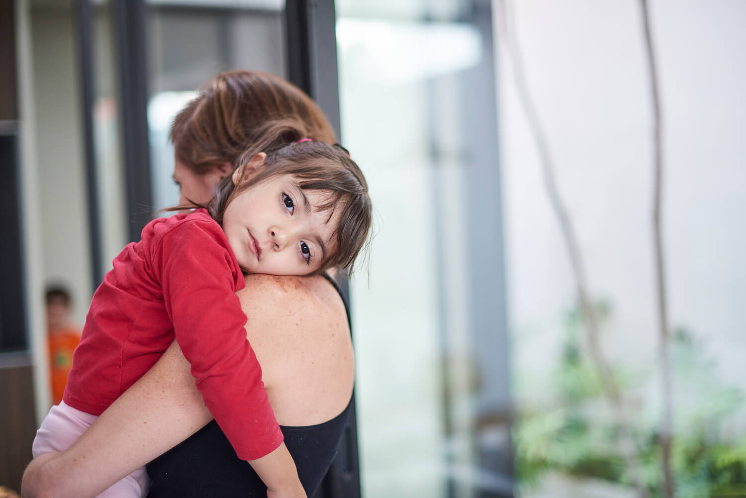 Mother carrying a young child, the child looks distressed and sad,