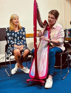 Bridget playing a harp, with her mother Melinda