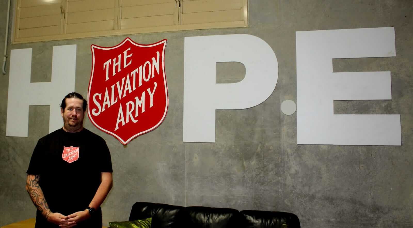 Eric standing in front of a wall with the Salvation Army shield, and the words 'HOPE' written on the wall.