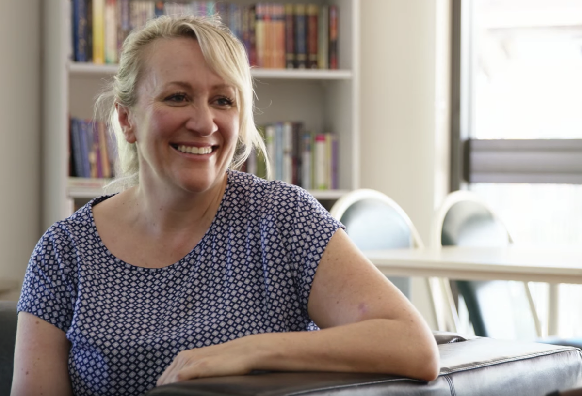 a woman smiles while sitting on a couch